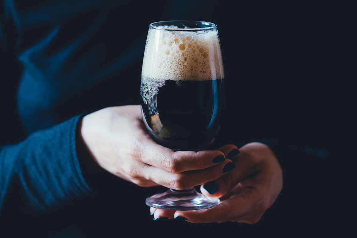 woman holding a dark beer.