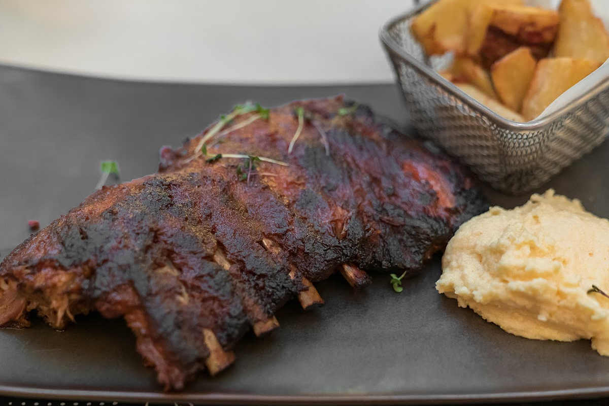 Grey platter with a slab of ribs, mashed potatoes and fries.