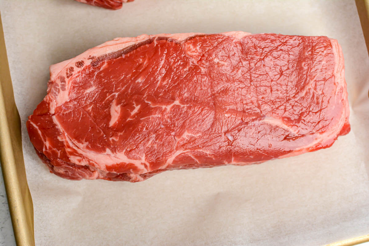New York strip steak on a sheet pan.