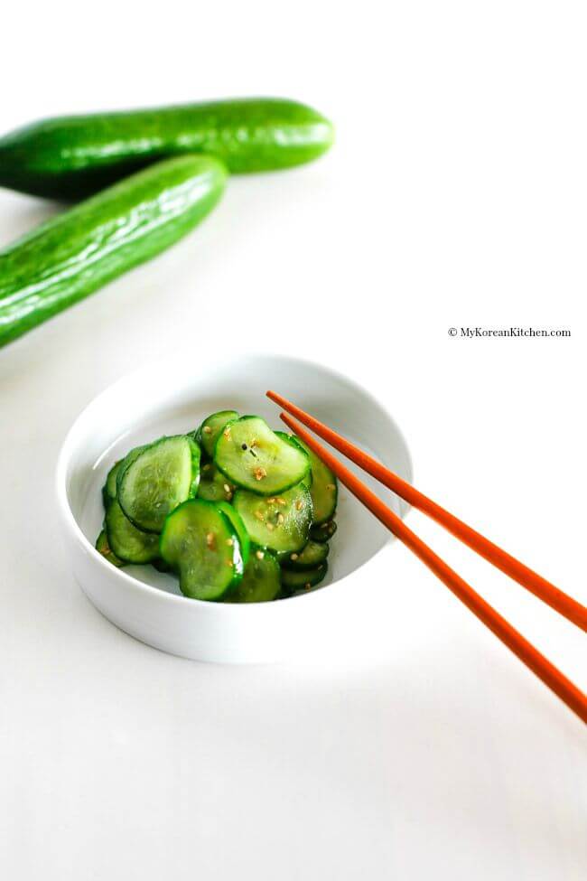 sautéed korean cucumbers in a white bowl with chopsticks.