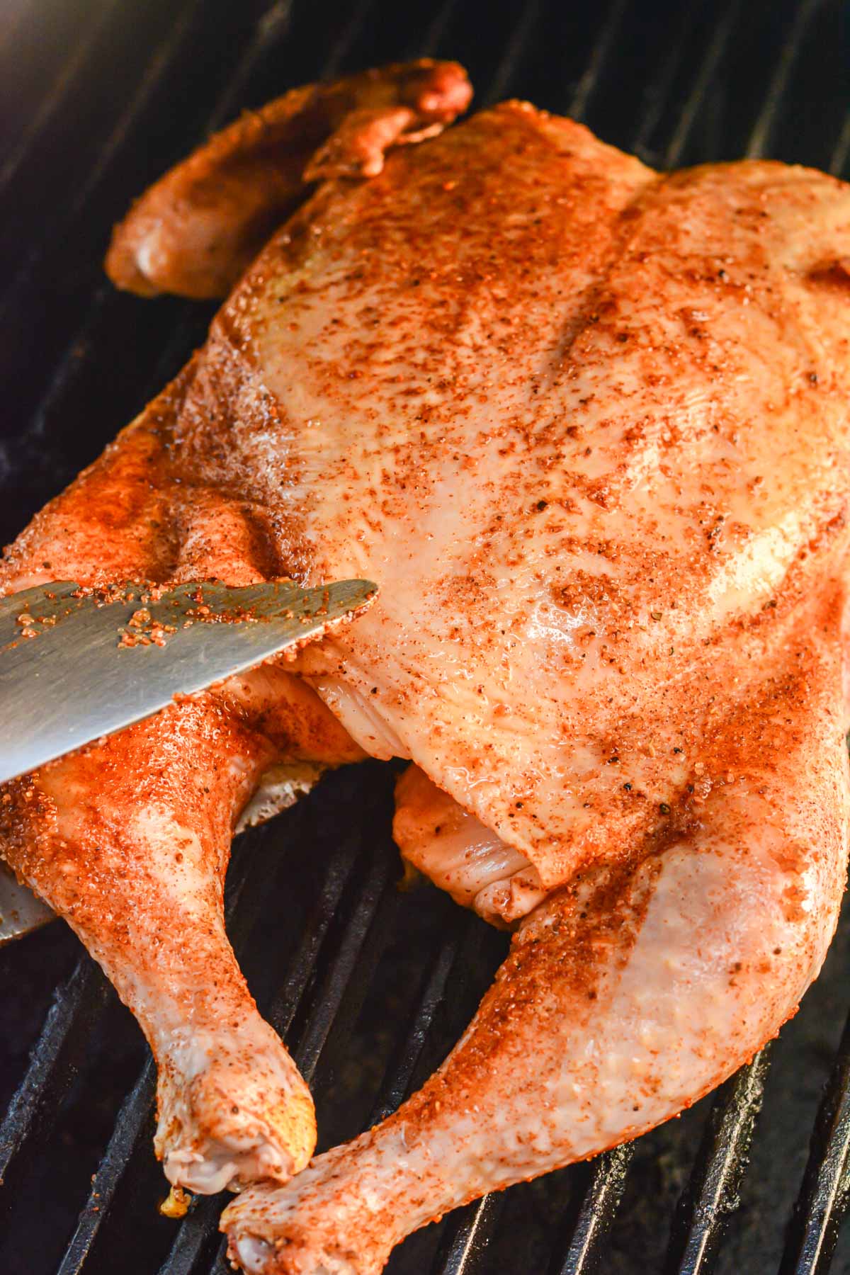 placing the seasoned chicken on the grill using BBQ tongs.