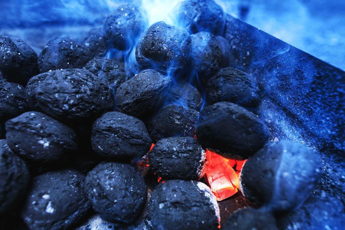inside a grill stacked with burning charcoal briquettes.