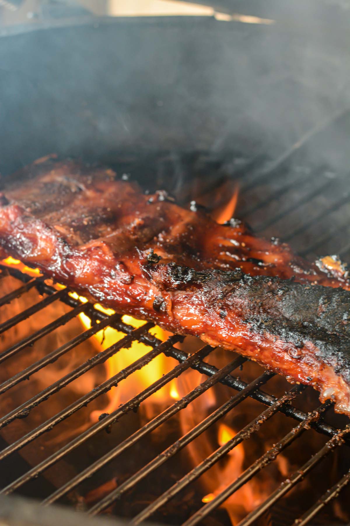 searing the grilled st louis ribs after it is removed from the foil wrap with flames kissing the slab.