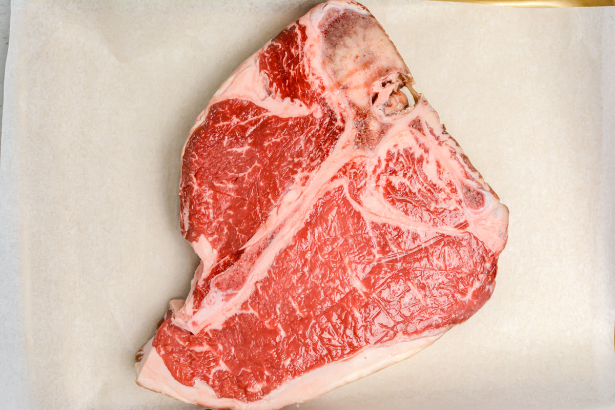 top down view of the porterhouse steak on a lines sheet pan.