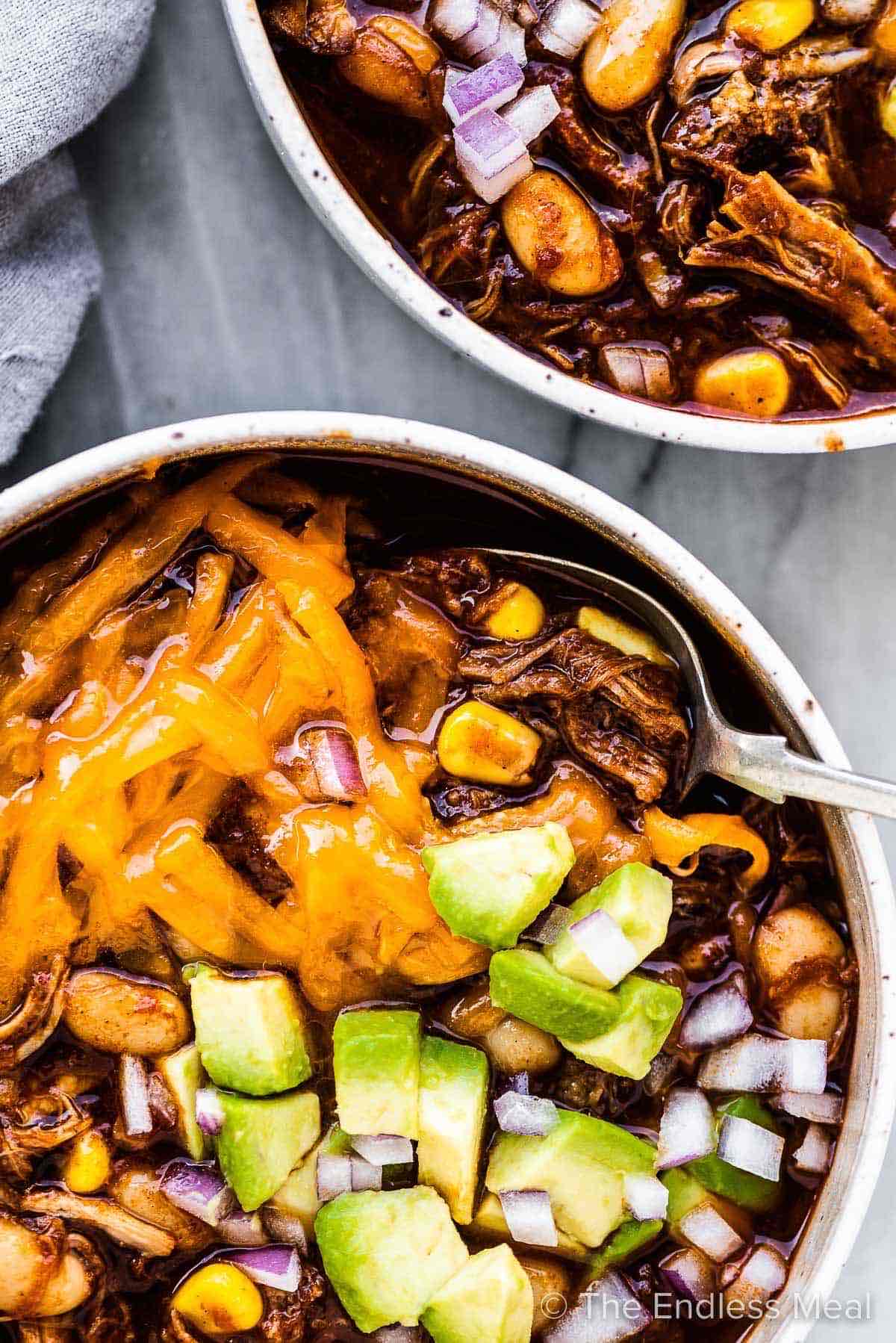 chili in a bowl with avocados on top.