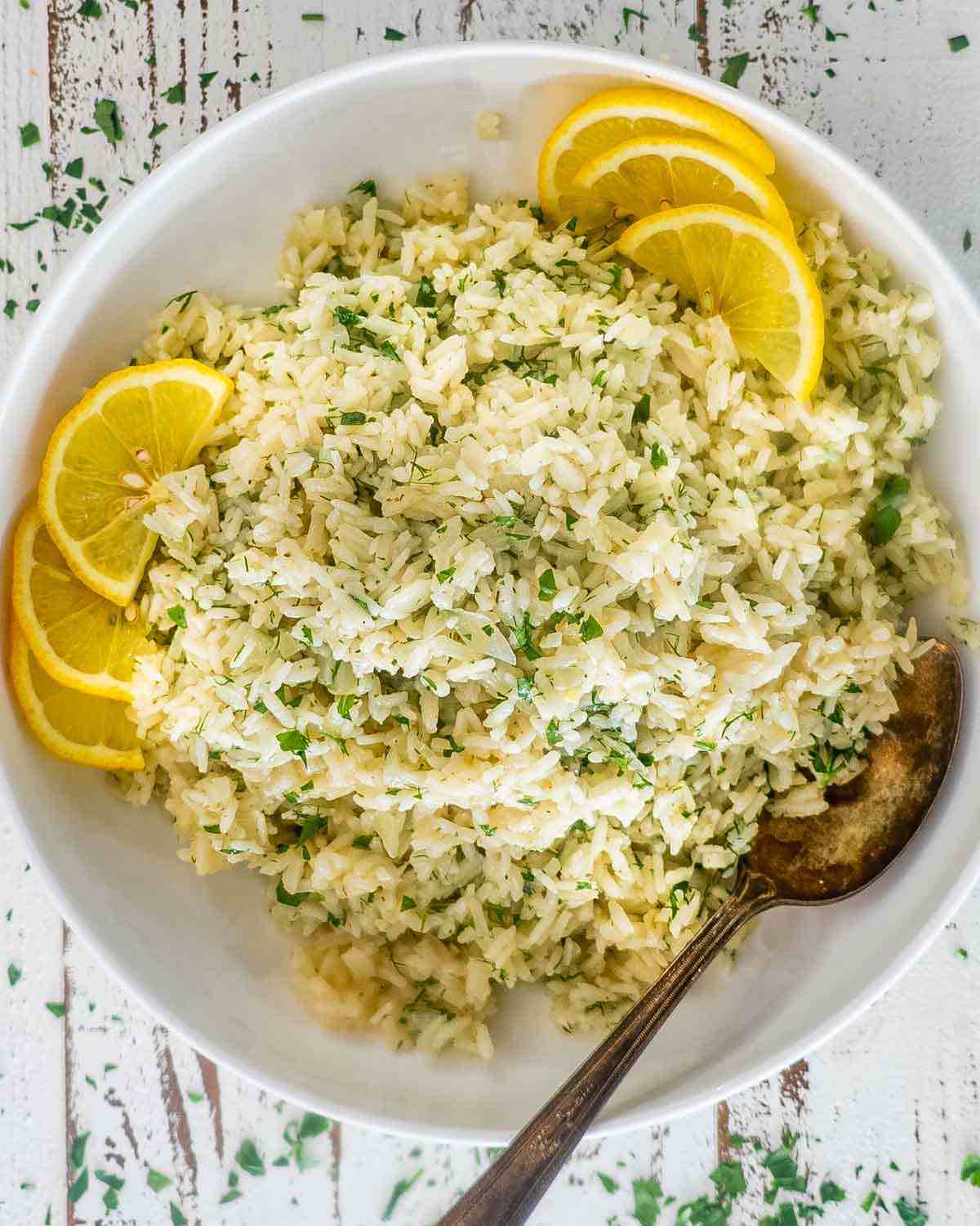 Rice and herbs in a bowl with lemons.