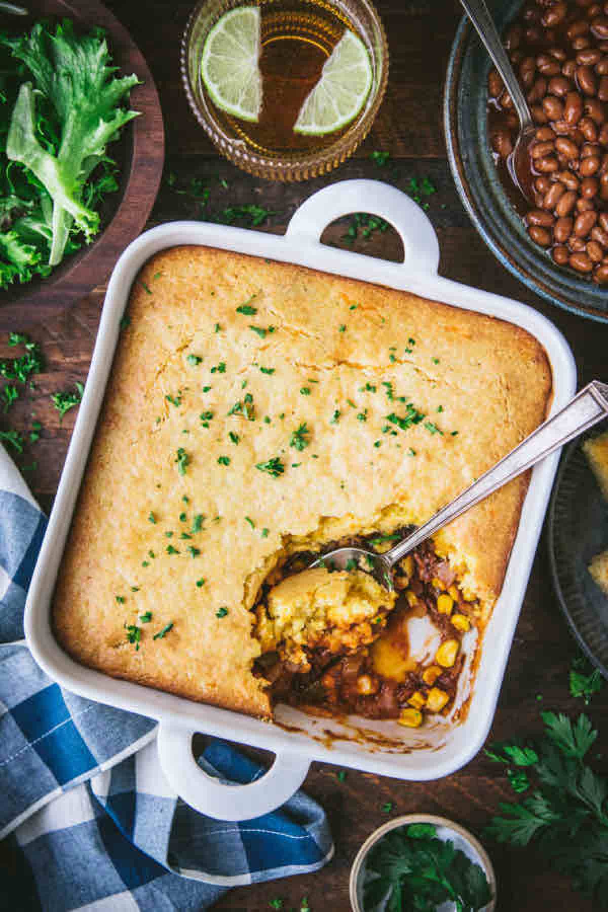 casserole in a square dish with beans and lettuce in the background.