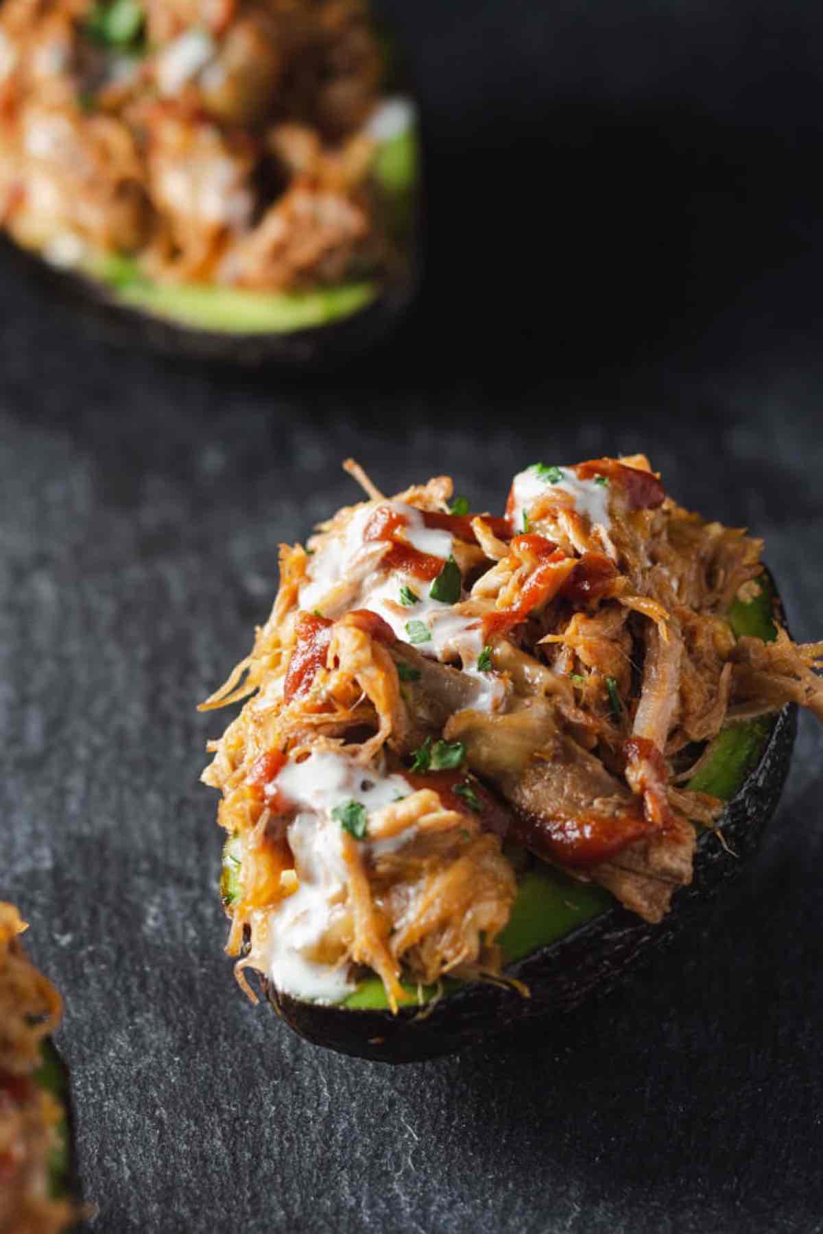 halved avocado filled with pulled pork and spice.