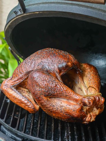 smoked turkey ready to be removed from the grill with a nice golden mahogany color.