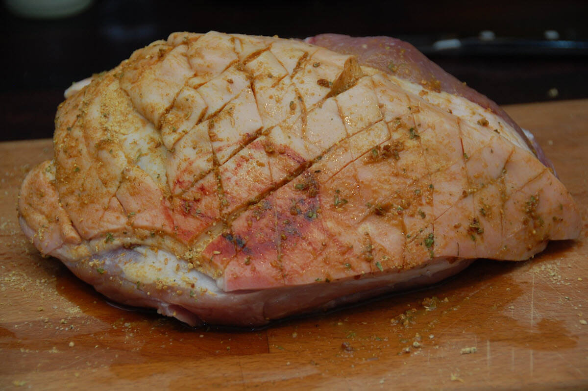 Raw seasoned pork shoulder on wooden table.