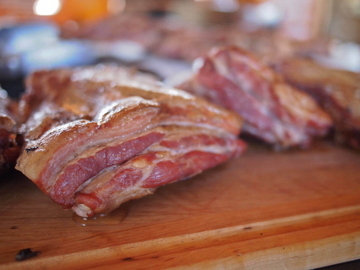 Whole smoked pork belly on wooden table.