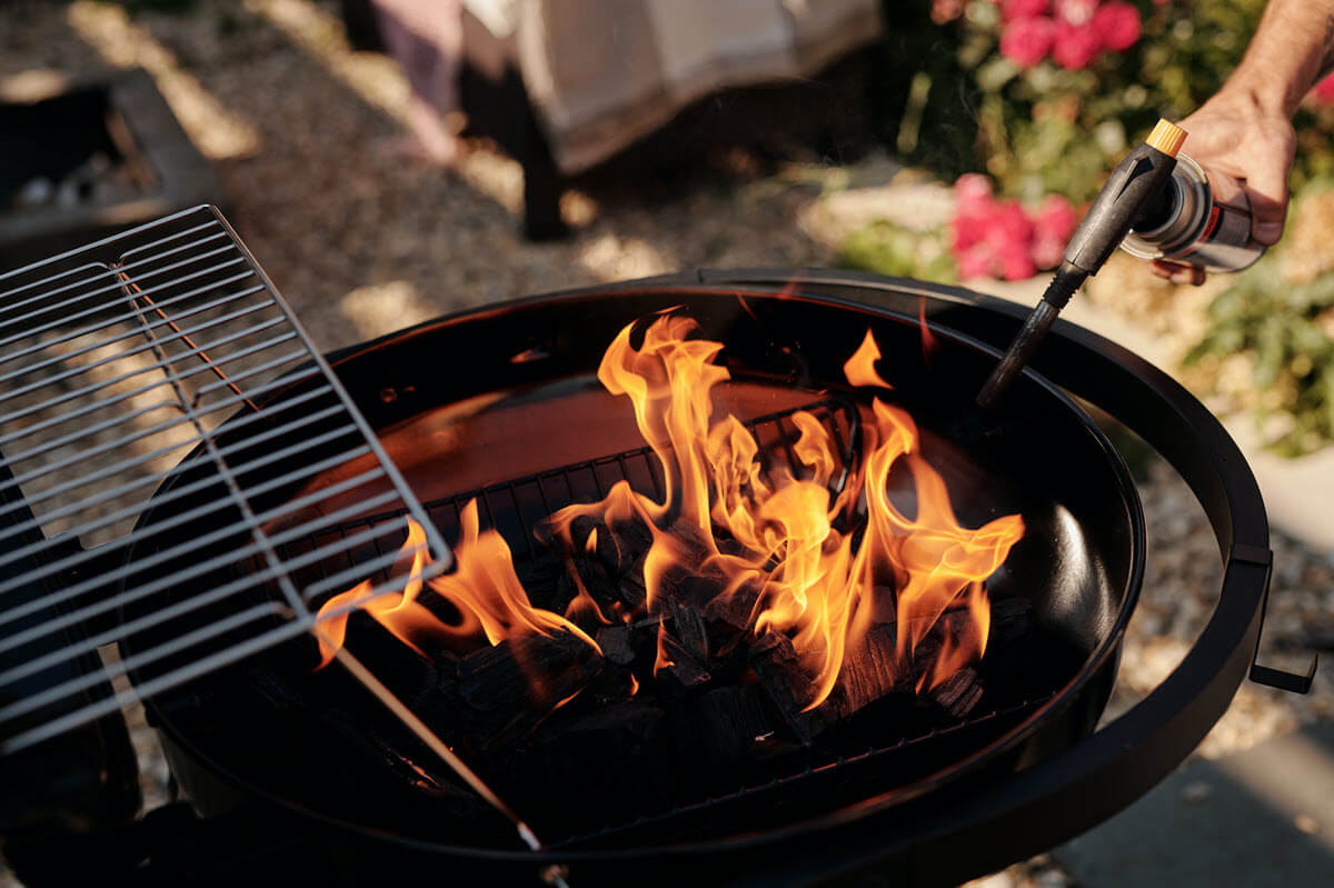 Burning charcoal with a torch for grilling.