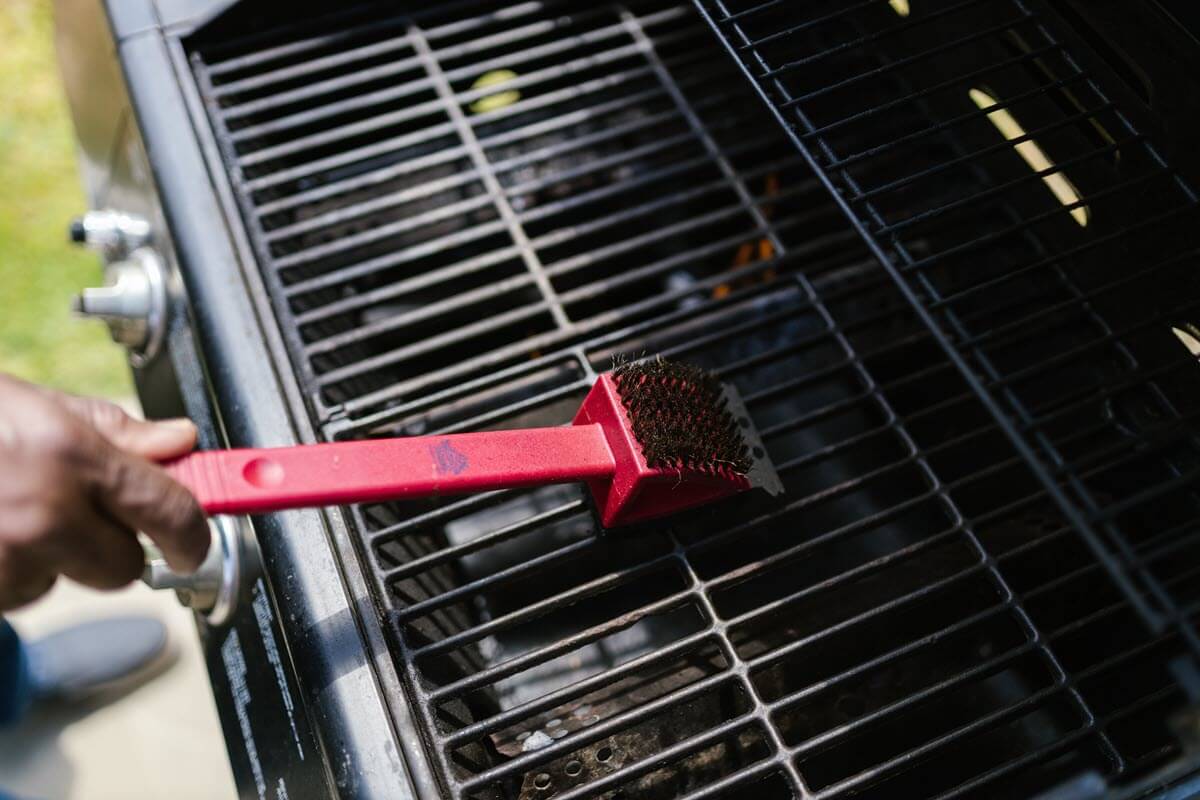 Cleaning grill with a wire brush.