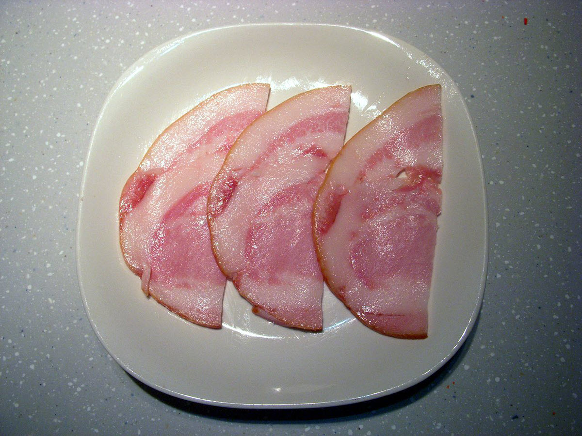 Slices of jowl bacon on ceramic plate.