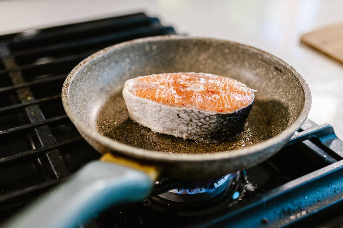 Pan frying salmon on stovetop.