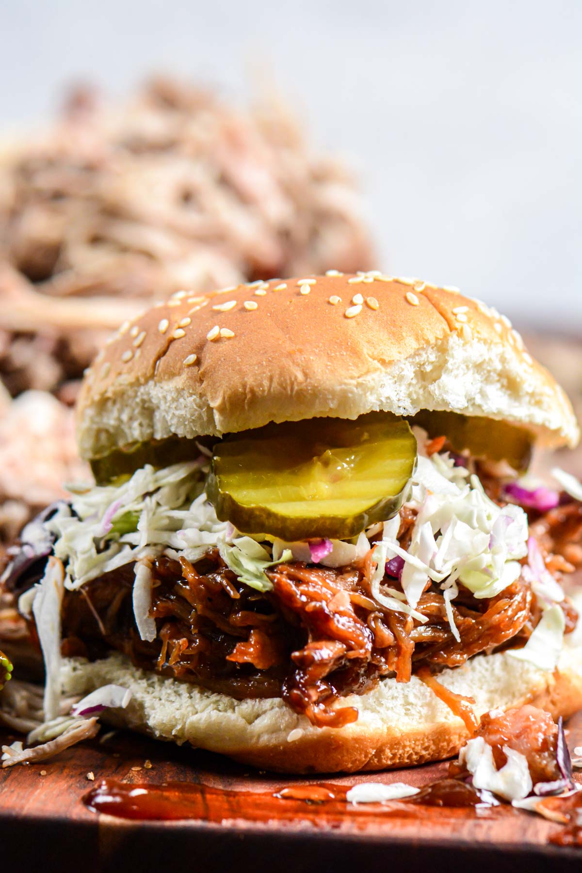 stack of pulled pork on a bun with bbq sauce.