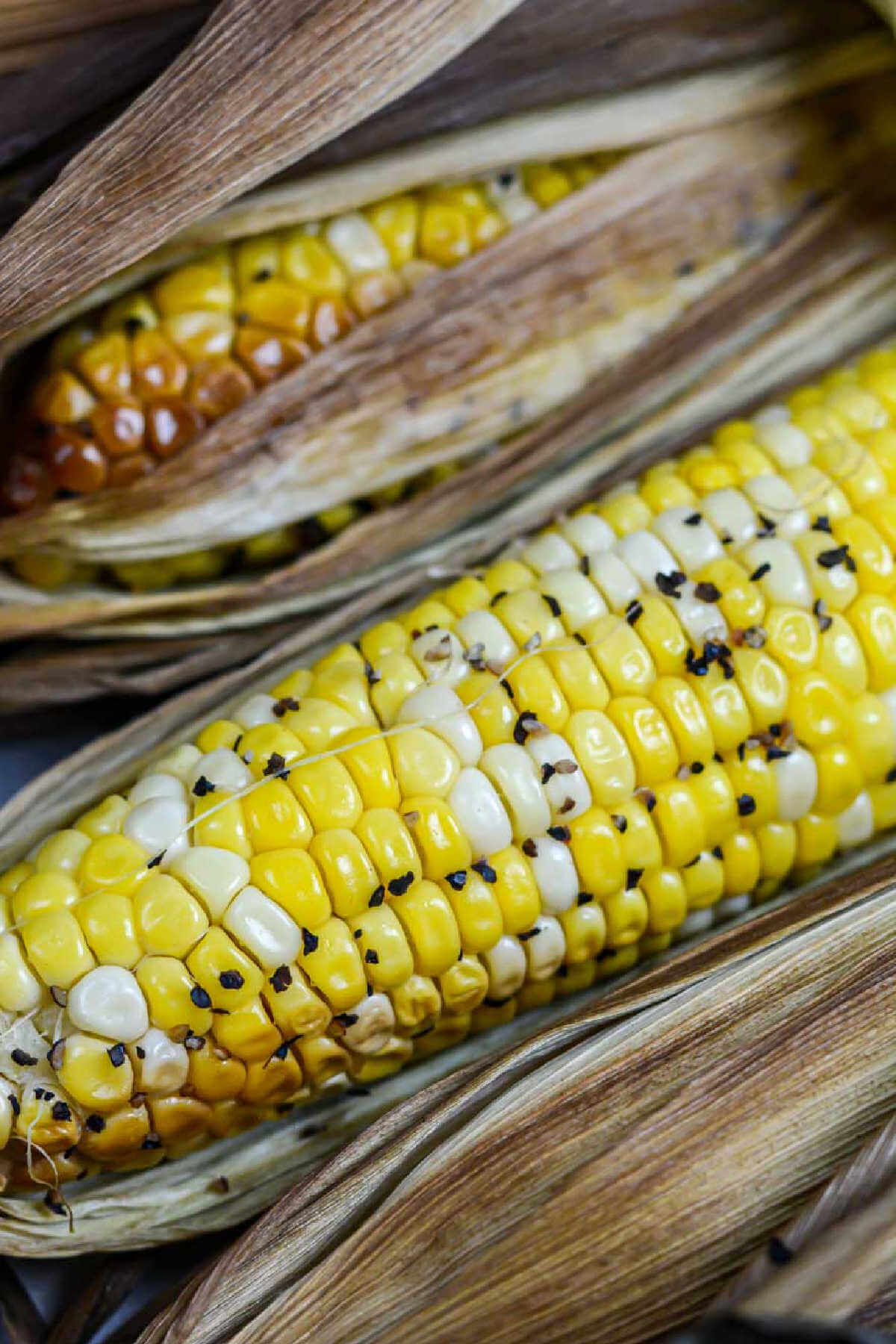 top down view of the smoked corn on the cob with butter and pepper after being removed from the grill.