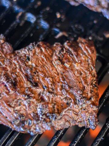 grilled steak over the hot coals on the big green egg showing the skirt steak marinade.