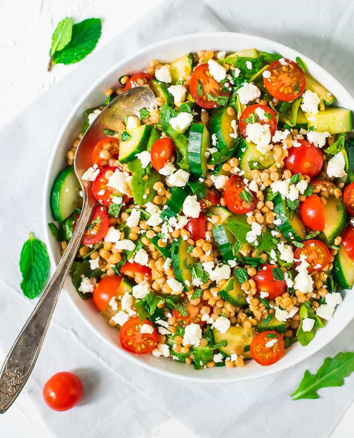 Top view of Israeli couscous salad with fresh veggies and herbs.