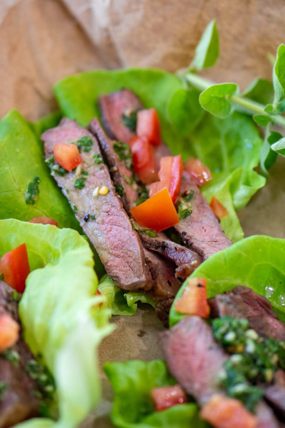 Chimichurri sauce on sirloin steak and lettuce wraps.