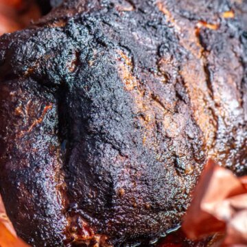 top down view of a smoked pork butt in the butcher paper after being removed from the grill.