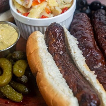 smoked sausage in a bun with mustard, pickles and potato salad.