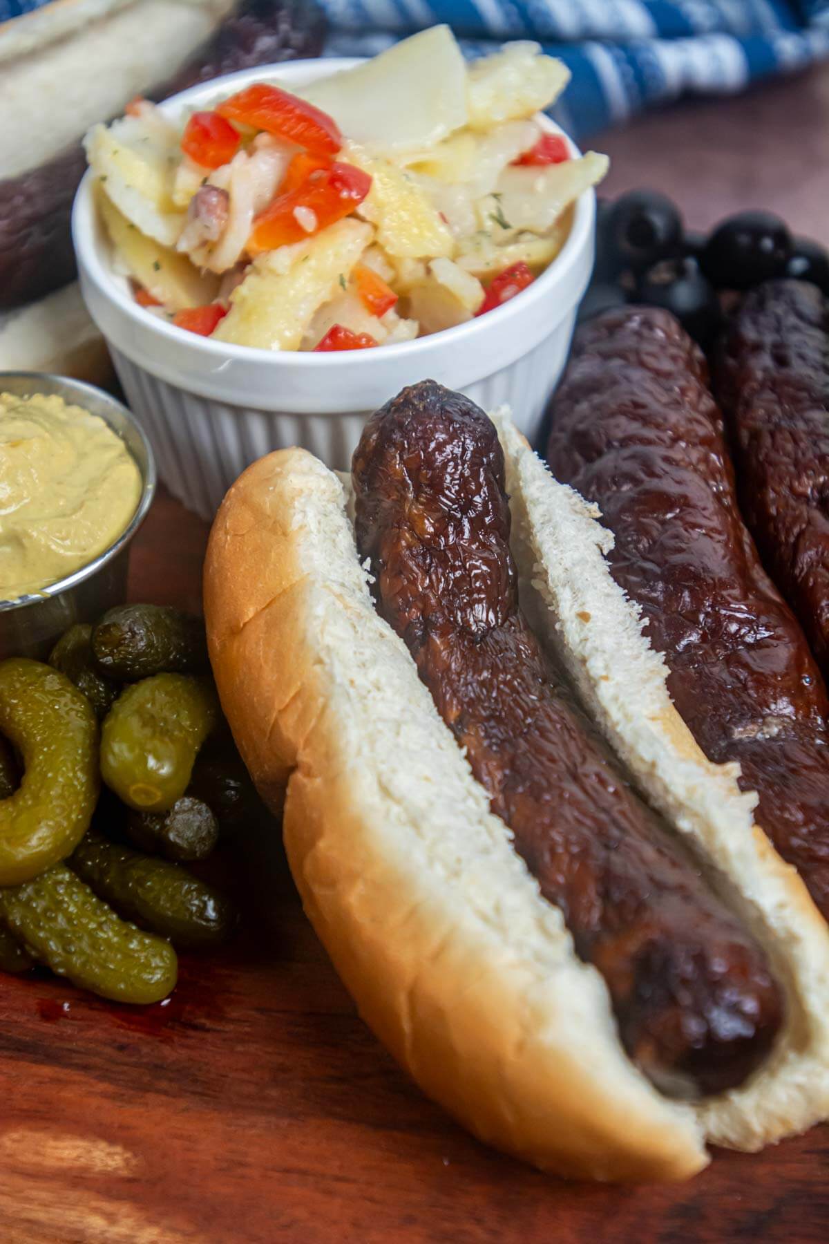 smoked sausage in a bun with mustard, pickles and potato salad.