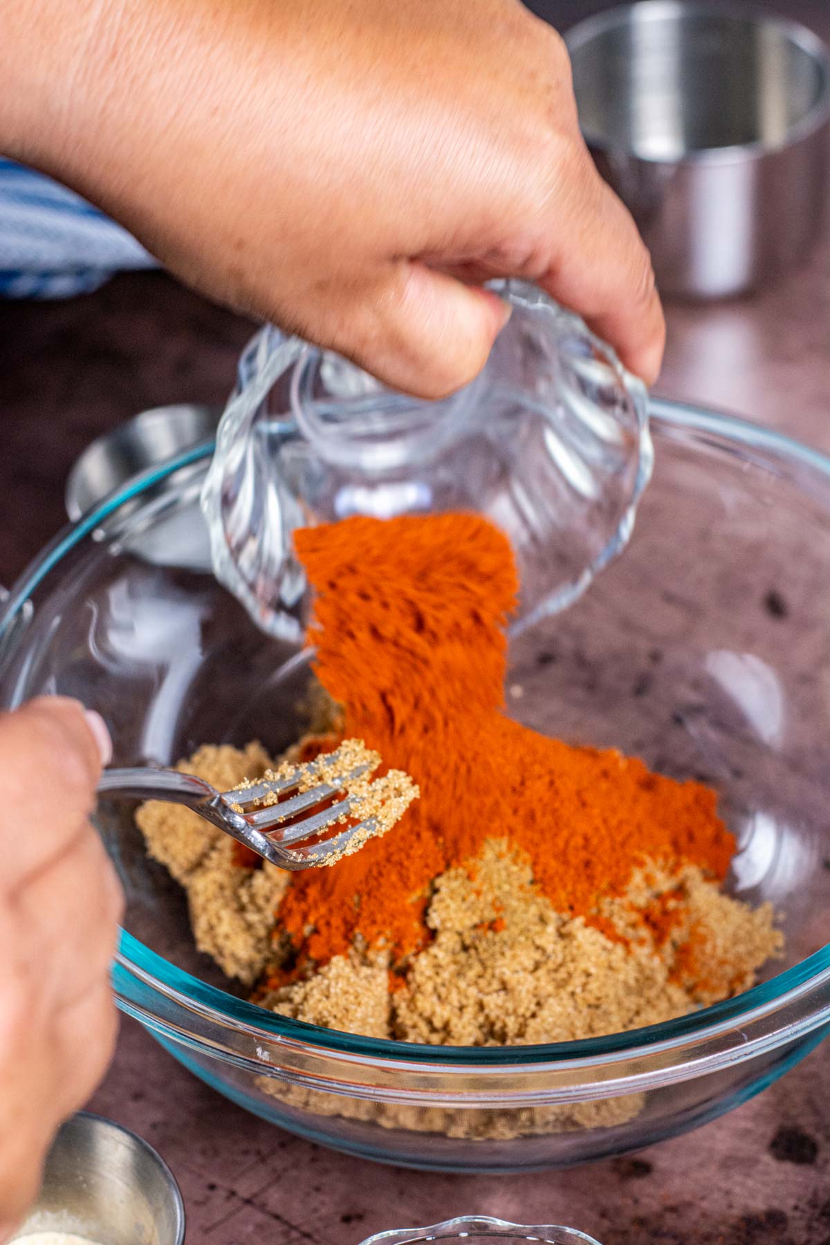 adding paprika to the rub in a glass bowl.