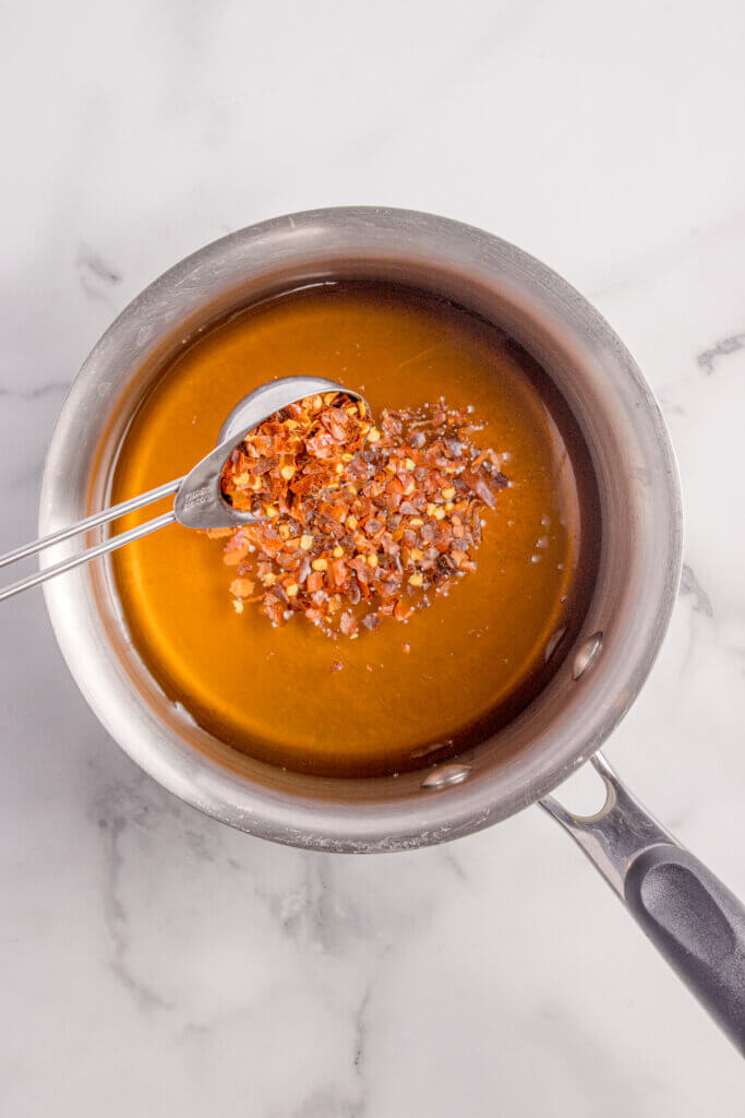 Adding red pepper flakes to the hot honey.