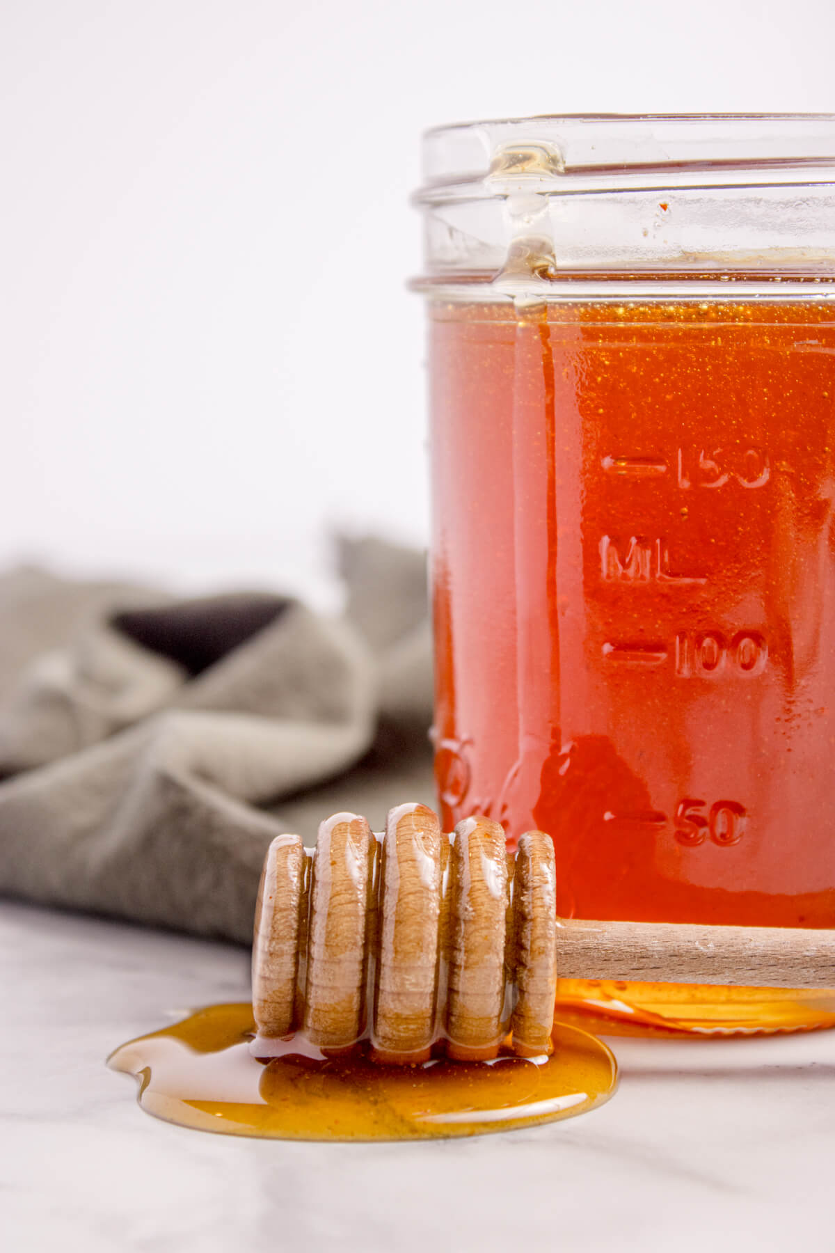 Hot honey in a mason jar with a honey spoon on the table.