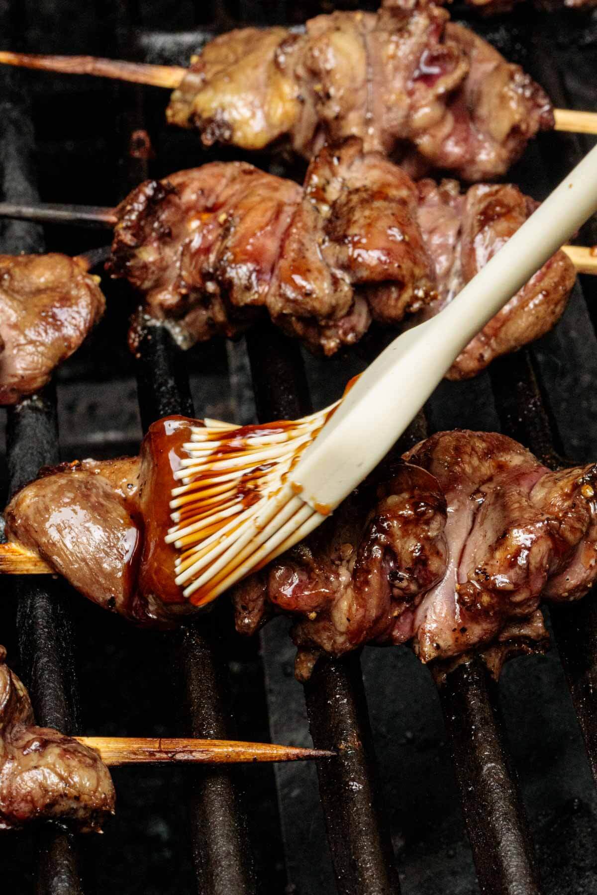 chicken hearts on the grill having a homemade teriyaki sauce brushed on.